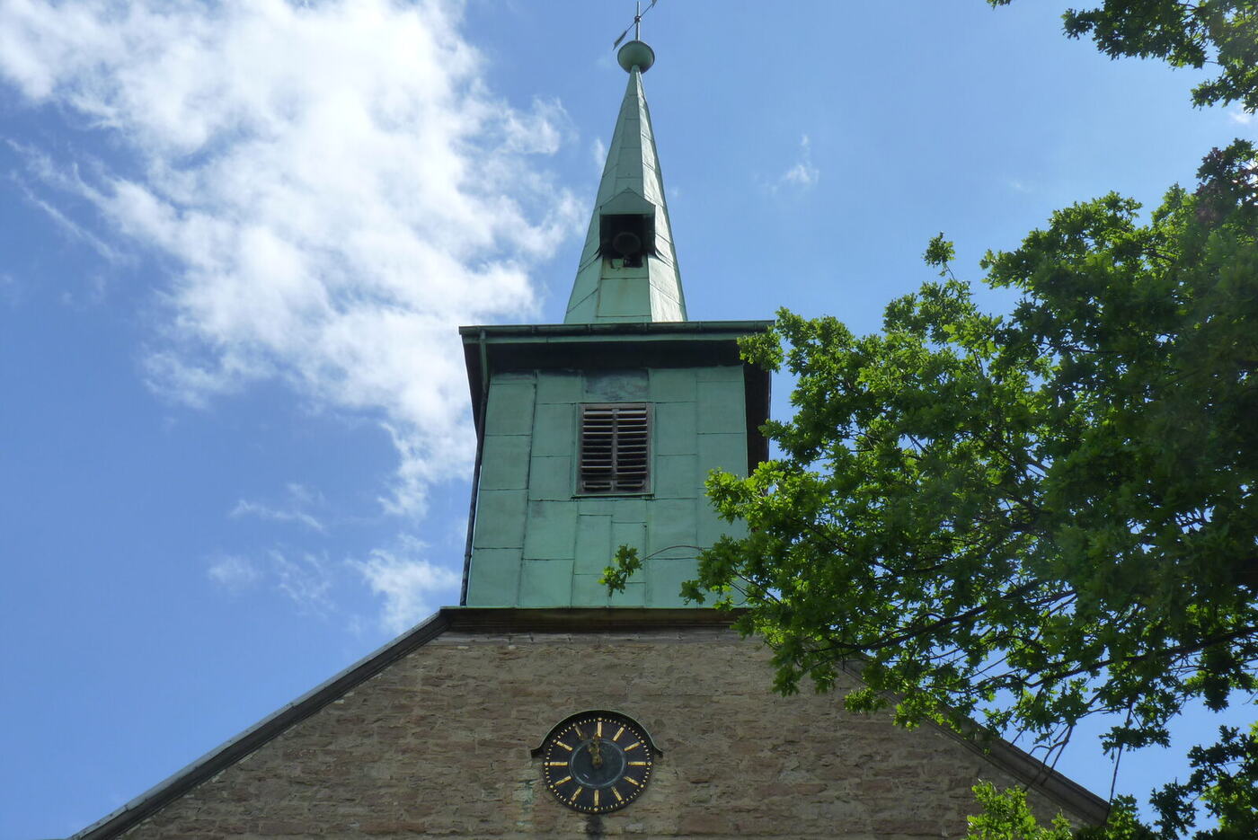 Der Dachreiter der Beuchter Kirche mit Turmuhr vor blauem Himmel