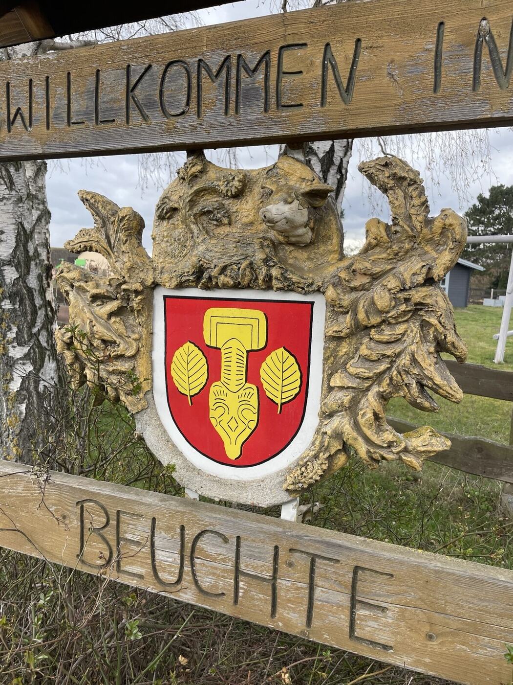 Geschnitztes Holzschild „Willkommen in Beuchte“ mit dem Ortswappen